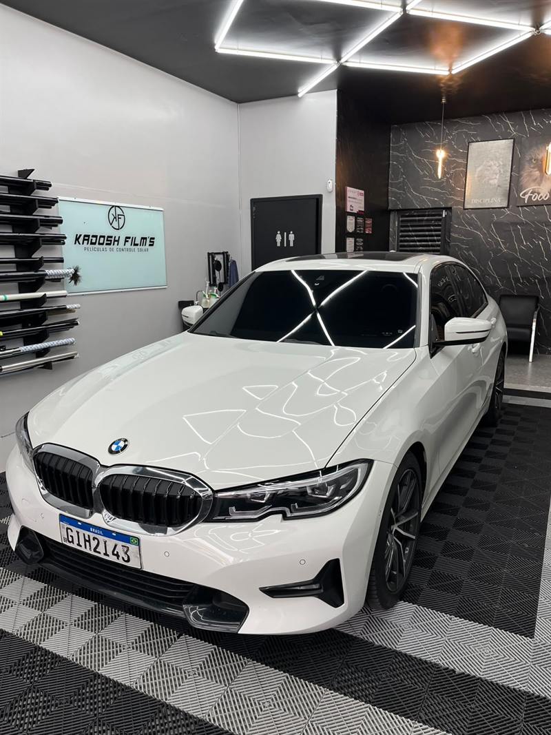 BMW branca dentro da loja Kadosh Film's com rolos de película na parede